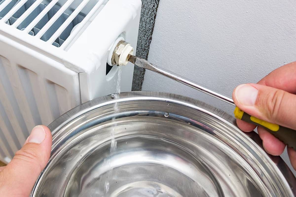 Action de purger un radiateur à eau pour évacuer l'air du circuit de chauffage.